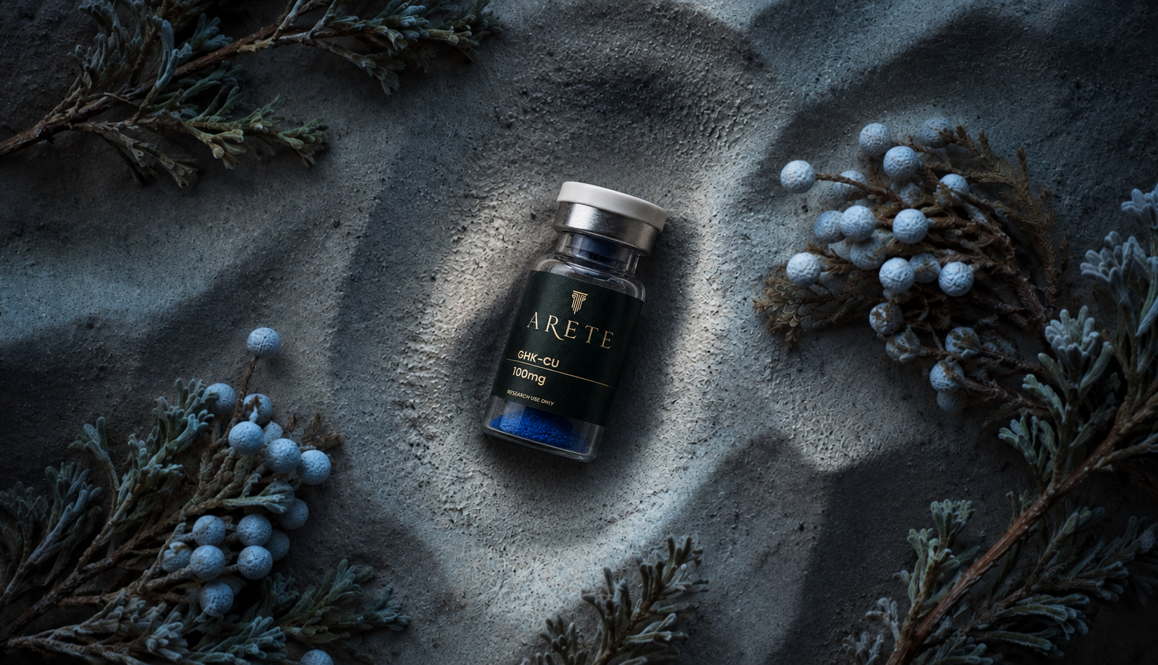 Arete GHK-Cu vial on stone surrounded by juniper branches